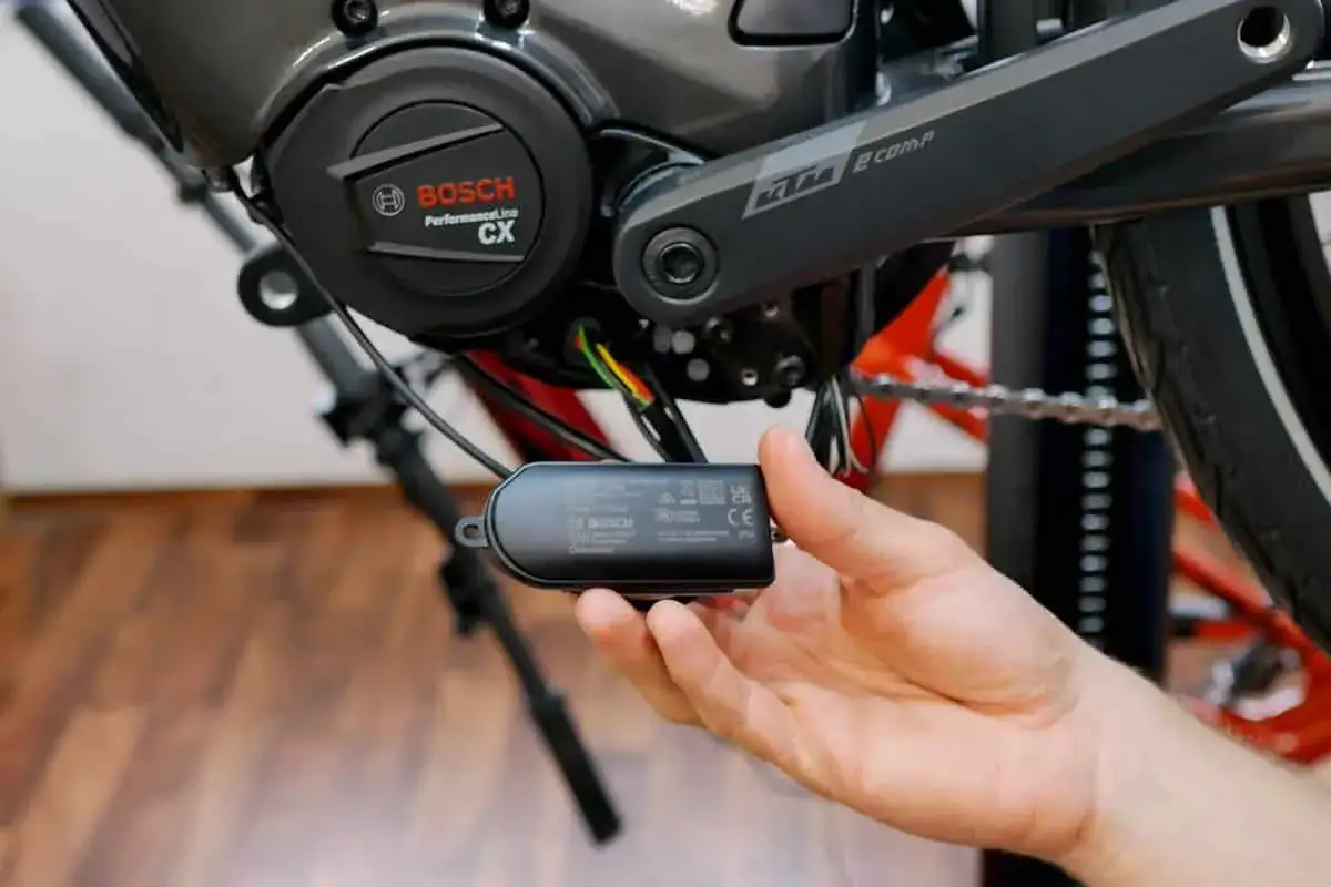 Hand hält Bosch Connect Modul zum Einbau am E-Bike Motor.