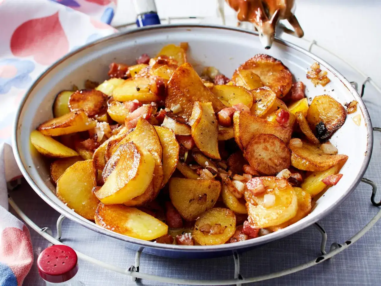 Herzhafte bratkartoffeln mit zwiebeln und Speckstücken in einer Pfanne, goldbraun gebraten und duftend.