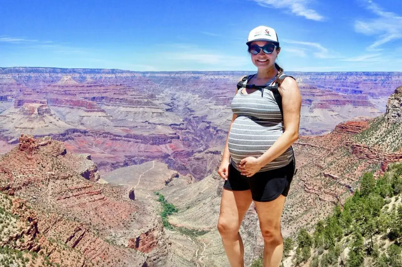 Mujer embarazada sonr&iacute;e en el Gran Ca&ntilde;&oacute;n, disfrutando de su aventura de viajar embarazada.