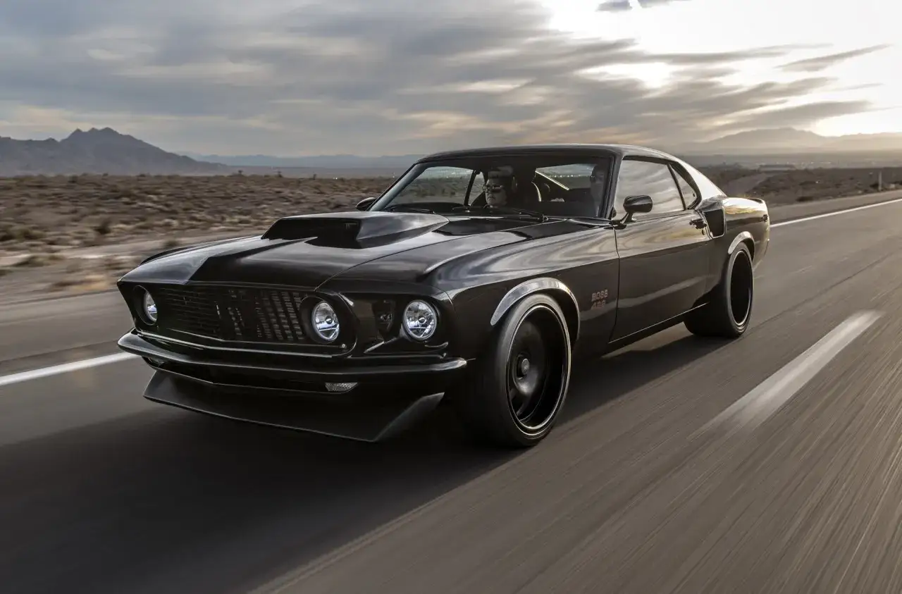 Svart Boss 429 Mustang kör på en öde väg i öknen.