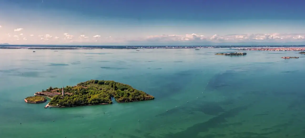 L'isola di Poveglia, con i suoi edifici storici e la vegetazione rigogliosa, si staglia nel mare turchese. Un luogo affascinante, l'isola di Poveglia si può visitare, offrendo scorci unici sulla laguna.