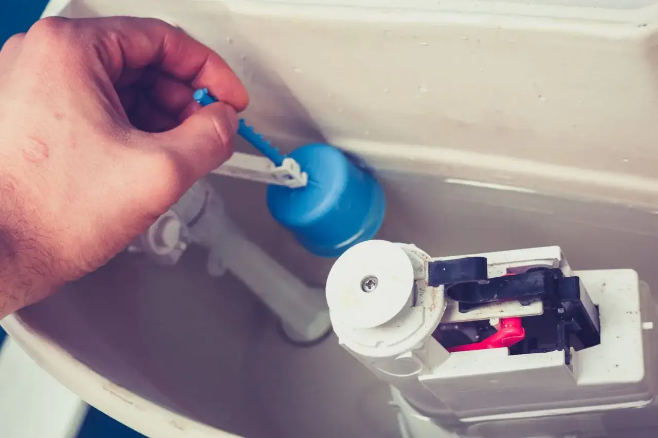 Main tenant ajuste le flotteur bleu pour changer la chasse d'eau.