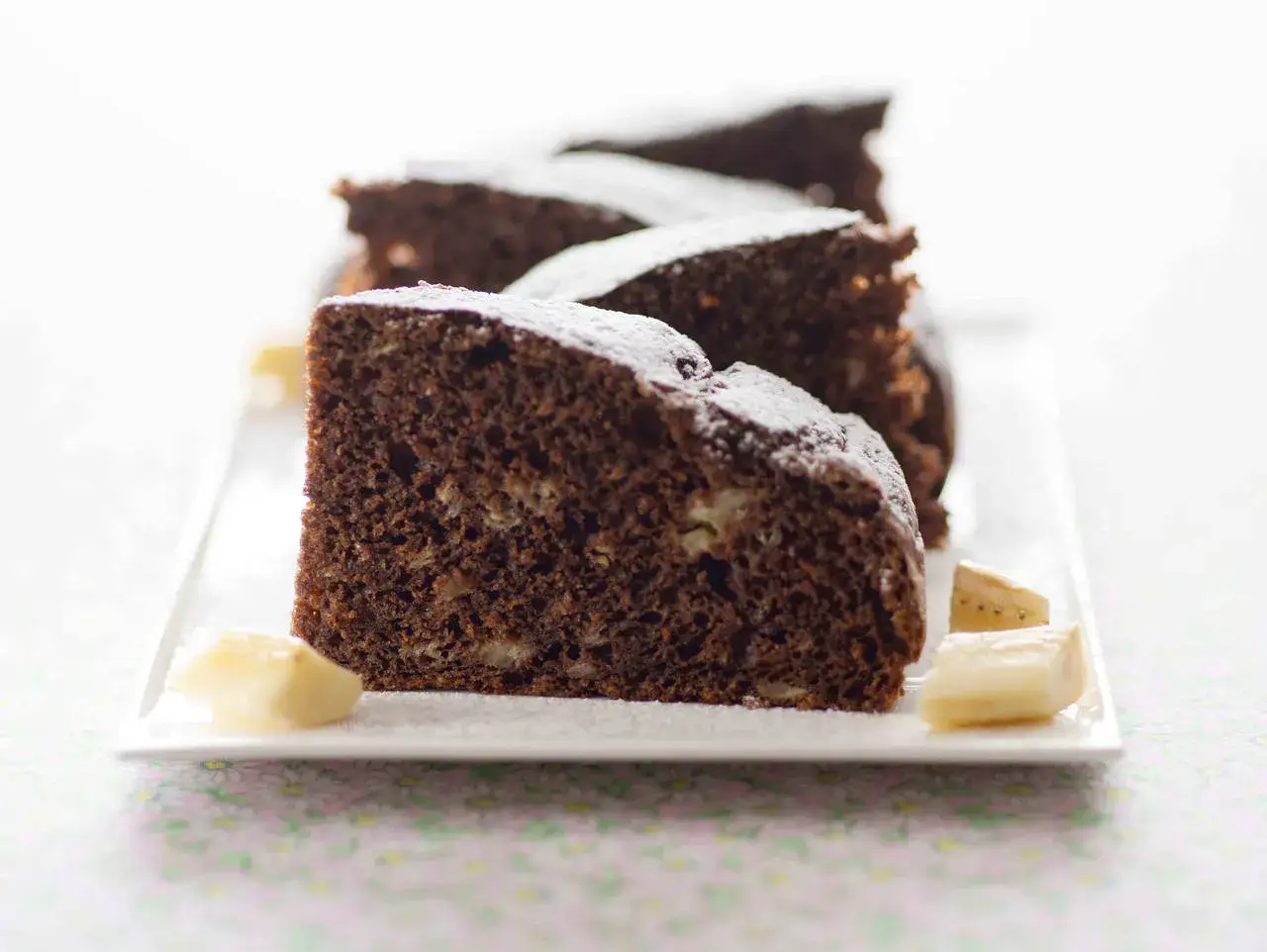 Fette di torta al cioccolato, come un **kopiec kreta** (montagna di talpa), cosparse di zucchero a velo e accompagnate da cubetti di banana.