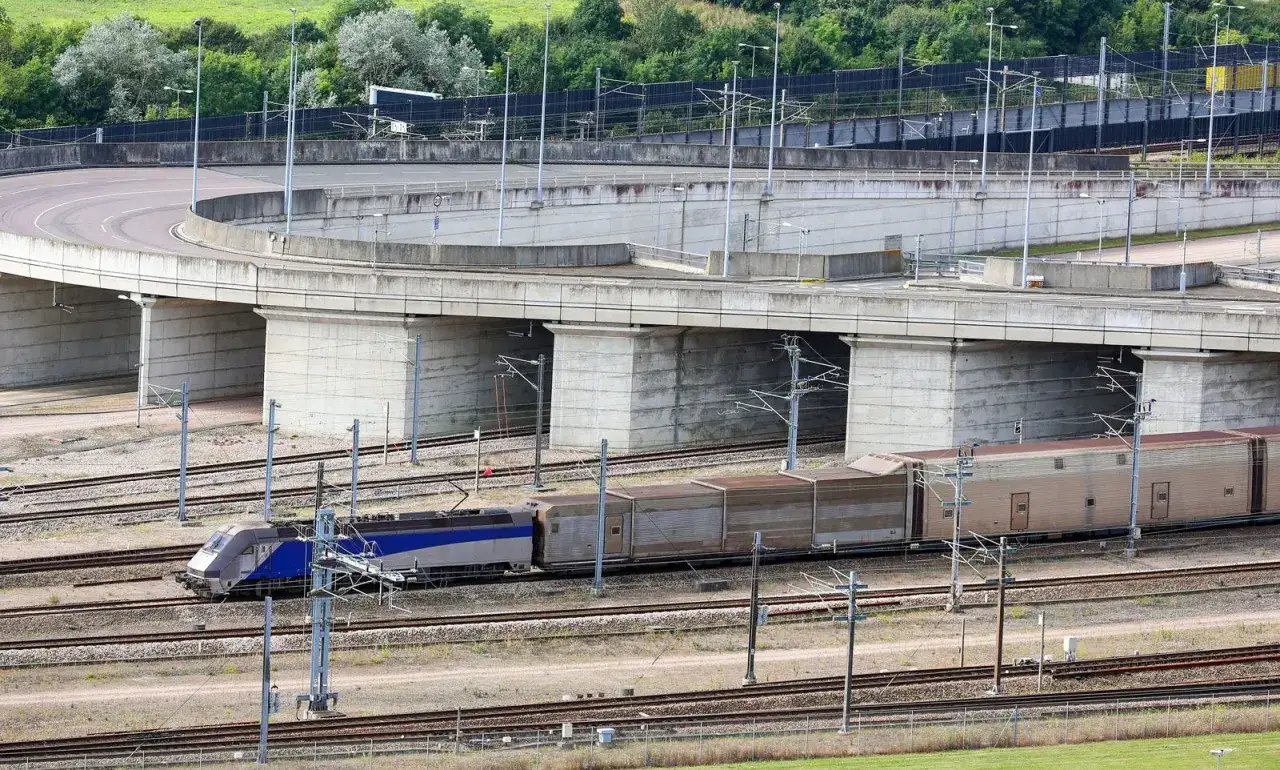 Pociąg pod Kanałem La Manche mknie po torach pod betonowymi wiaduktami.