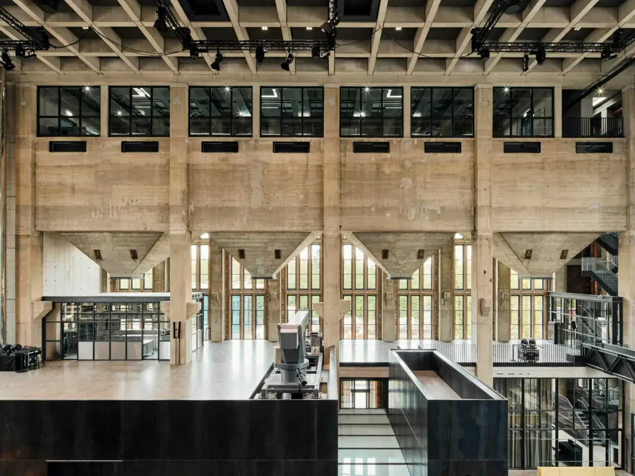 Gro&szlig;er, offener Raum mit industriellem Charme und innovativer Architektur. Betonw&auml;nde, Stahltr&auml;ger und Glasfronten pr&auml;gen das Bild.