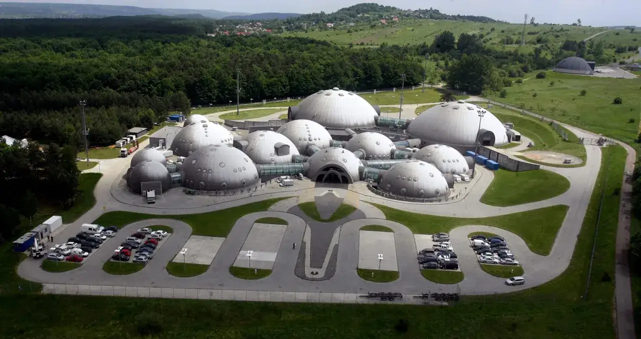 Kompleks kopuł przypominający bazę na planecie Alwernia, otoczony zielenią i lasem.