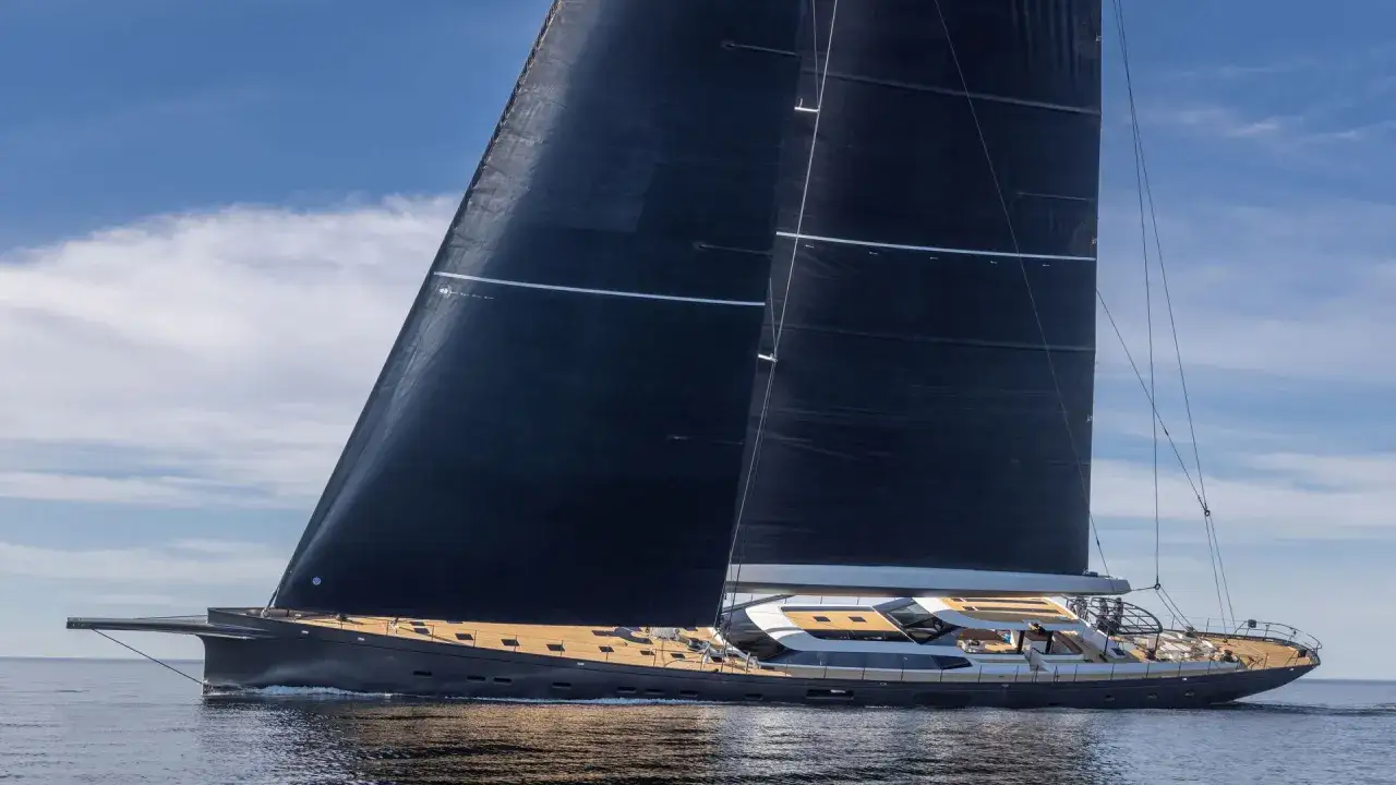 Eine elegante Segelyacht mit schwarzen Segeln gleitet über ruhiges Wasser. Die pink gin vi ist ein Traum auf See.