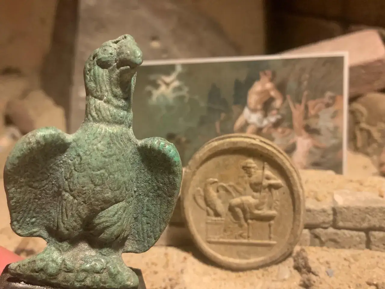 En bronsörn och en medaljong med en sittande figur. Kanske en ledtråd till vem är Zeus, himlens och åskans gud.