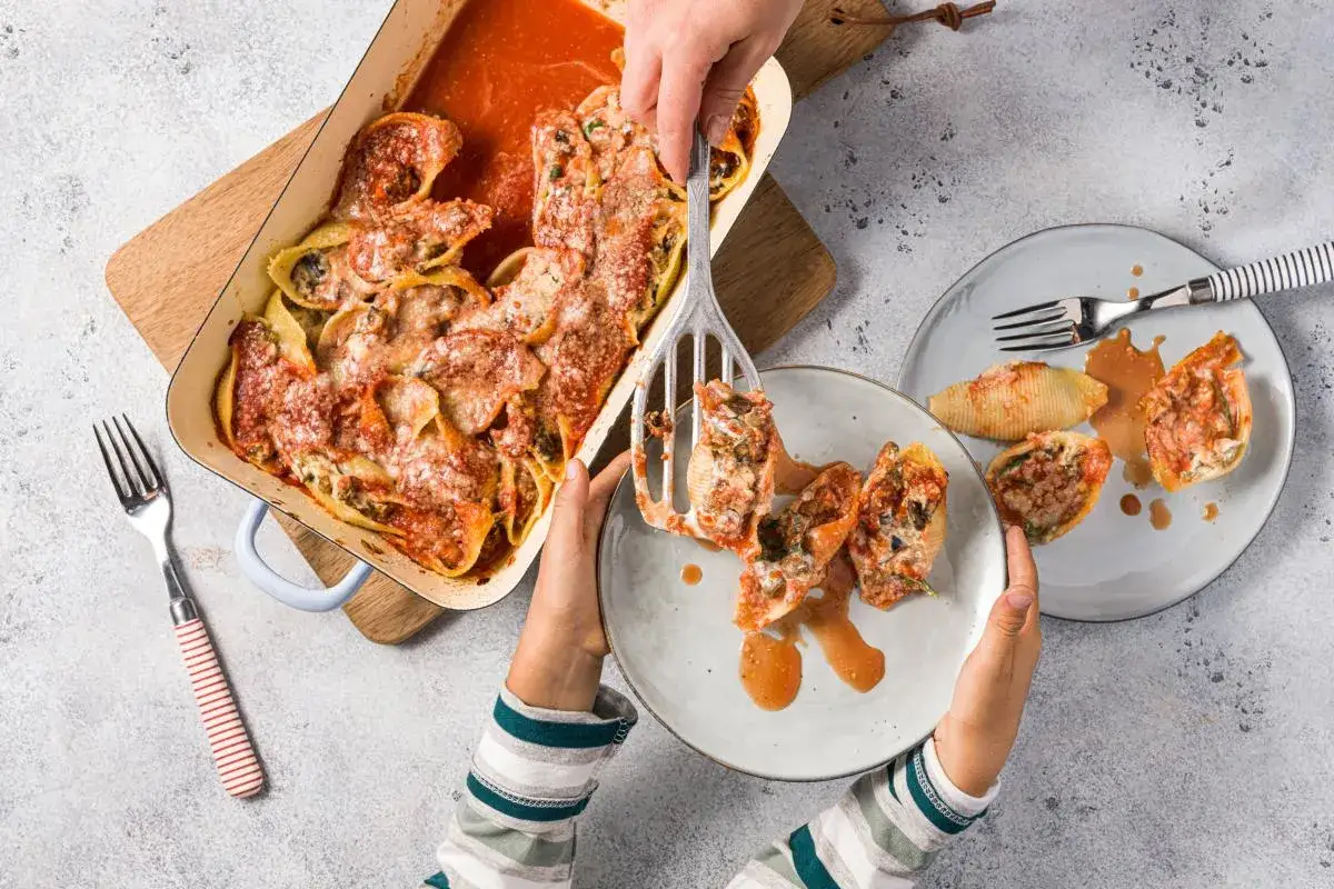 Conchiglioni à la sicilienne, généreusement garnis et gratinés, servis dans un plat et sur des assiettes.