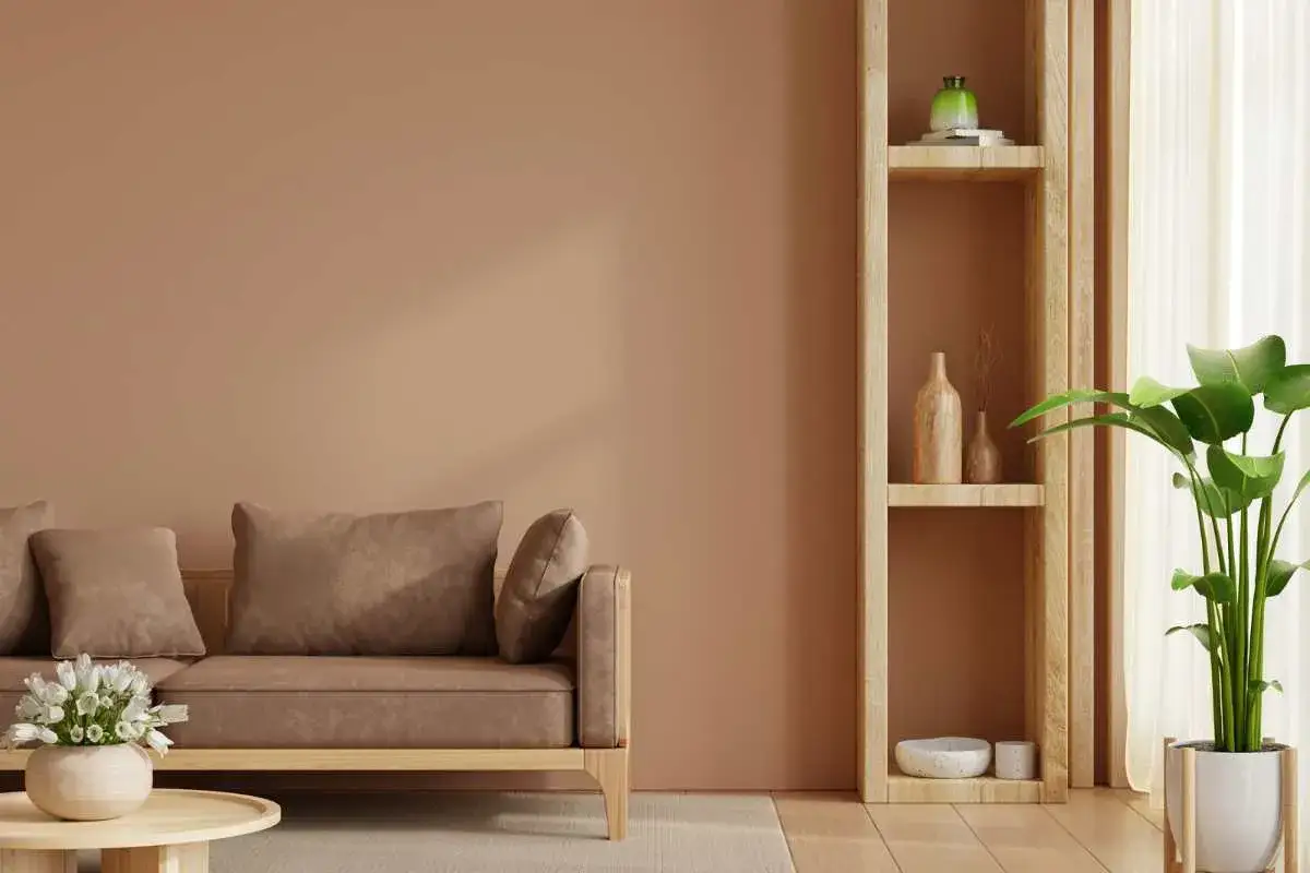 Sof&aacute; marr&oacute;n y estanter&iacute;a de madera en un espacio con **colores c&aacute;lidos**. Una planta verde aporta un toque de frescura.