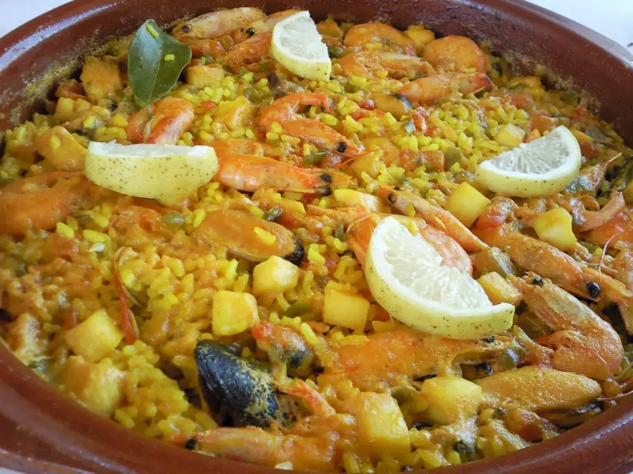 Arroz con berberechos, gambas y mejillones, decorado con gajos de limón y hojas de laurel. Un plato lleno de sabor.