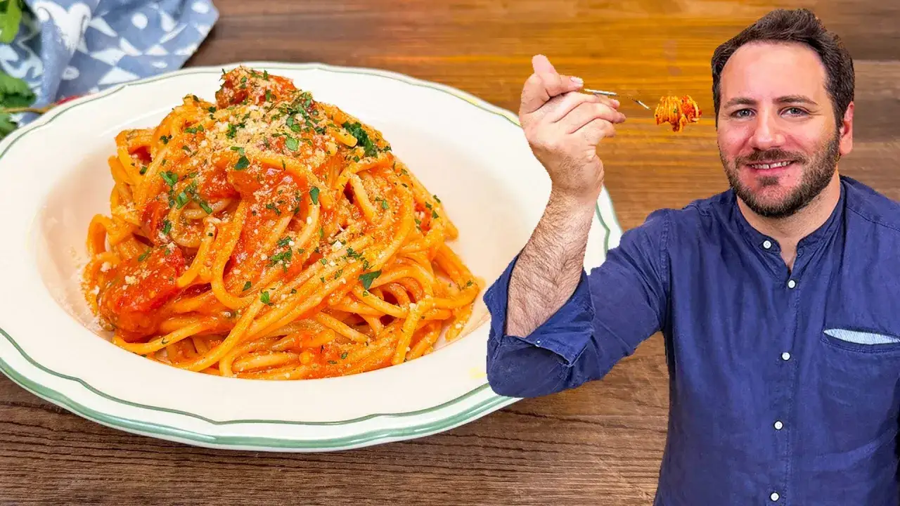 Un uomo sorride mentre assaggia spaghetti alla corte d'assise, un piatto ricco di sugo e parmigiano.