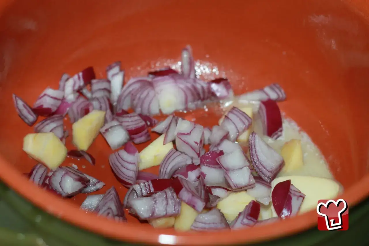 Rotkohl wie lange kochen? Hier werden Zwiebeln und Apfelst&uuml;cke in einer orangen Sch&uuml;ssel vorbereitet, bereit f&uuml;r die Zubereitung.