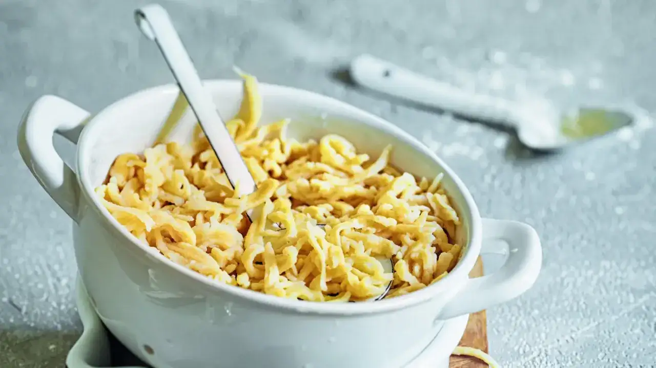 Herzhafte Spätzle in einer Schüssel, perfekt für alle, die glutenfrei essen möchten. Ein Löffel liegt bereit.