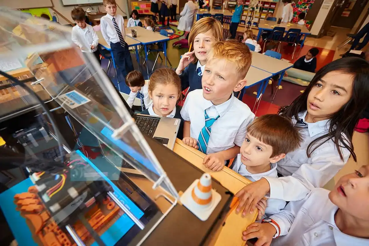 Children gather around a 3D printer, engaged in 3D printing education. Their curious faces reflect the excitement of learning through technology.