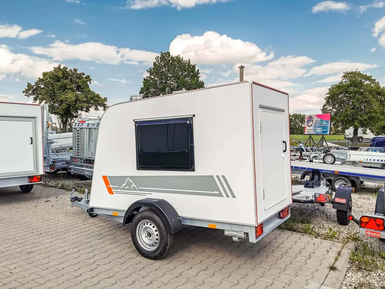 Mała przyczepa kempingowa z grafiką górską, idealna na kamping. Gotowa na przygody!