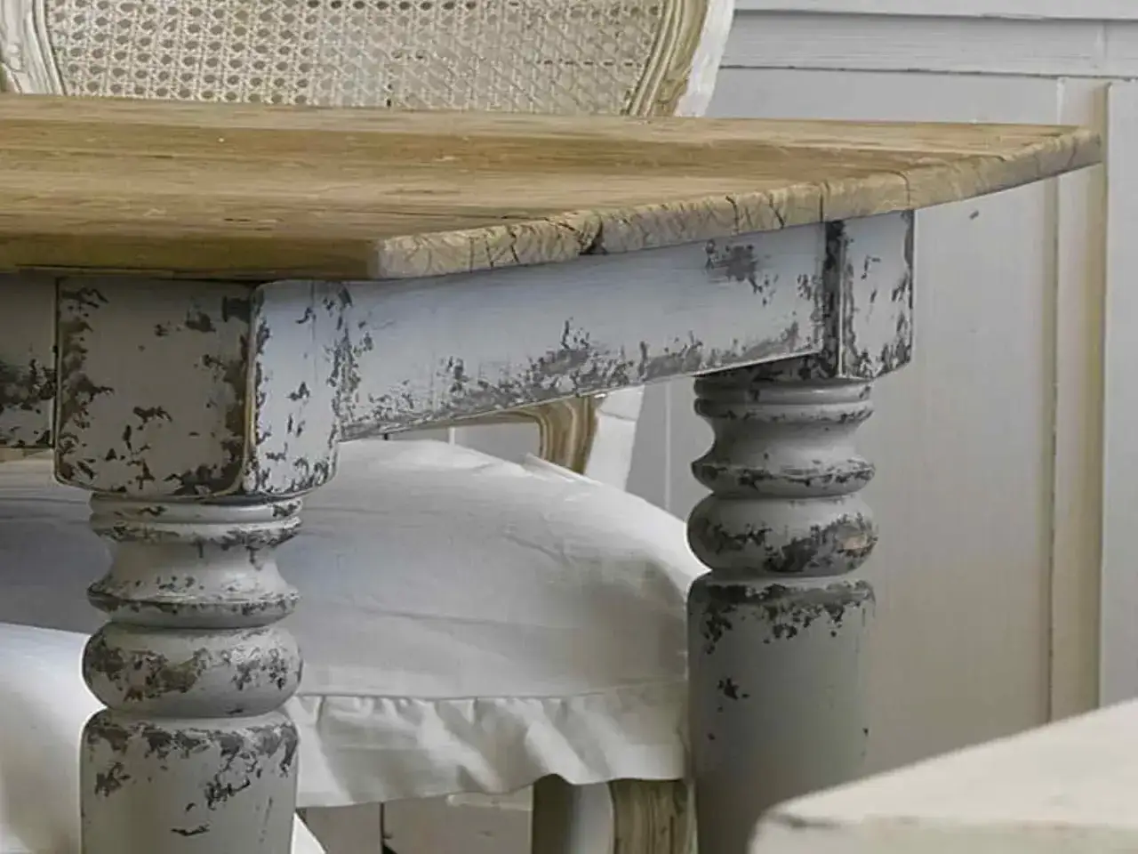 Dettaglio di un tavolo in legno con gambe tornite, verniciate in grigio chiaro con effetto invecchiato, perfetto per chi vuole imparare come restaurare un mobile antico in stile shabby.