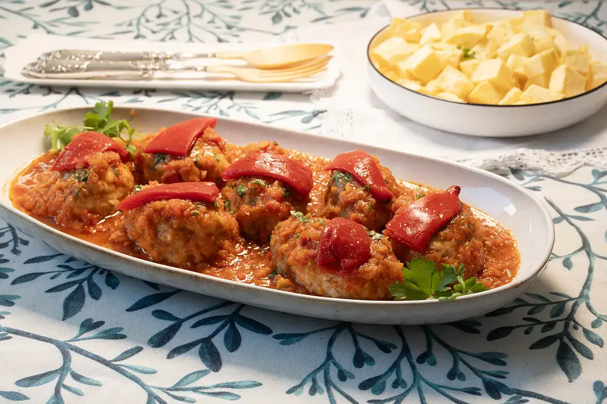 Sabrosos albóndigas en salsa de tomate, coronadas con pimiento rojo. Un delicioso rollo de bonito listo para disfrutar.