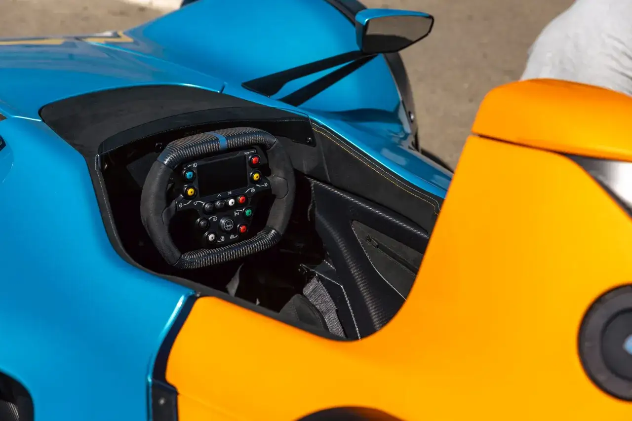 Cockpit eines BAC Mono Rennwagens in Blau und Orange. Das Lenkrad ist mit Carbon und Alcantara bezogen.