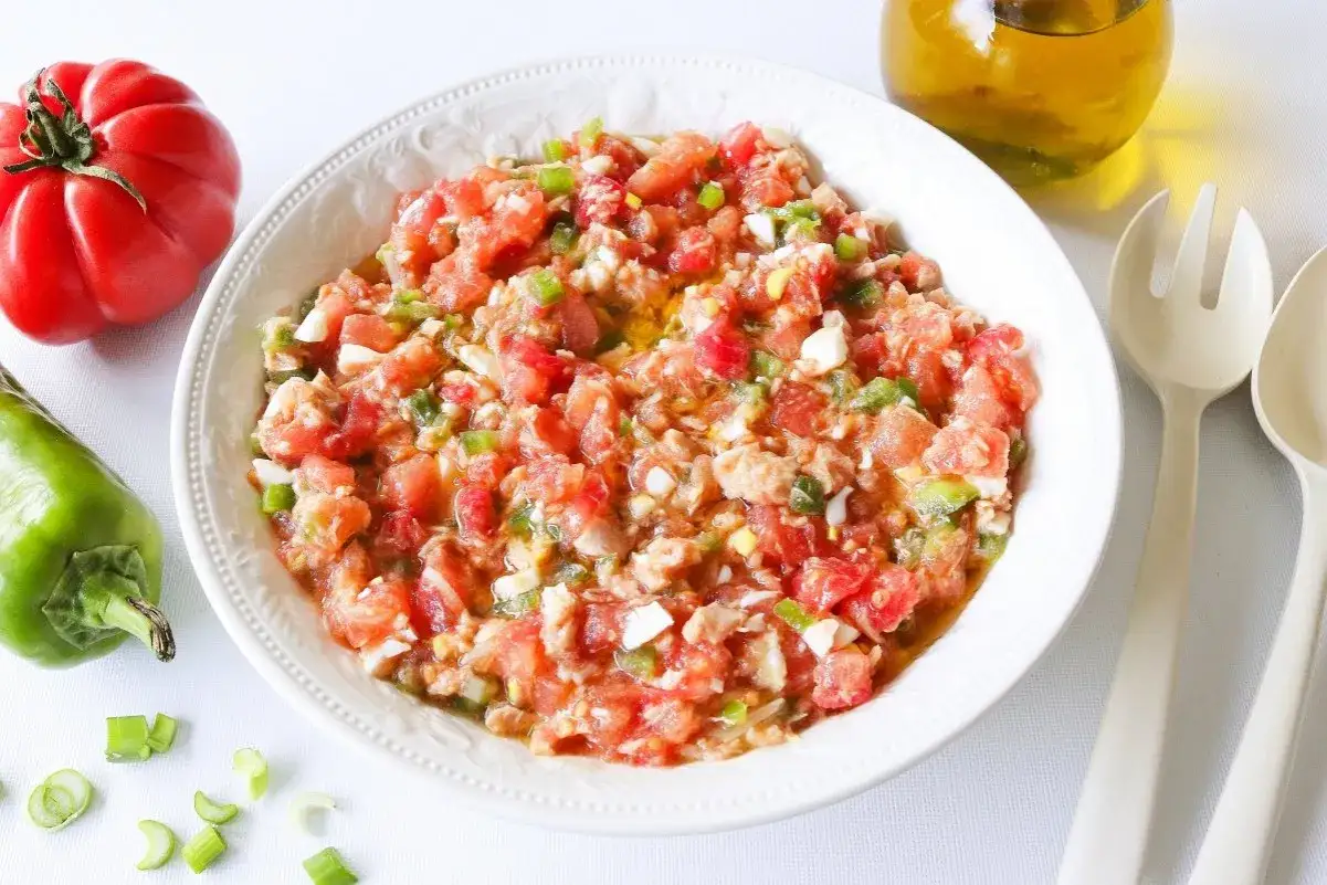 Ensalada pipirrana fresca y colorida, con tomate, pimiento verde, huevo duro y cebolleta, lista para servir.