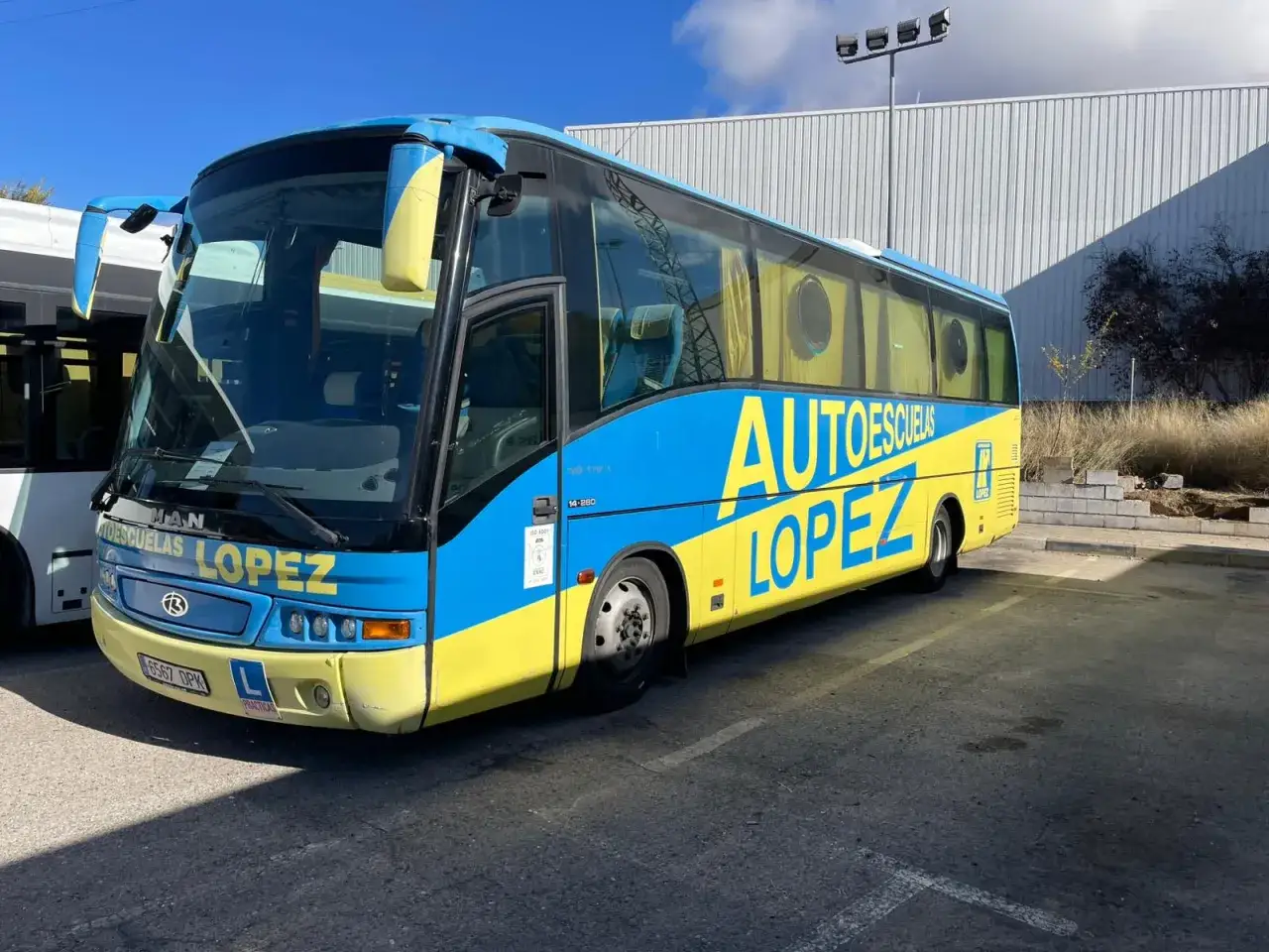 Autobús azul y amarillo de Autoescuelas López, listo para conducir un autobús y aprender.
