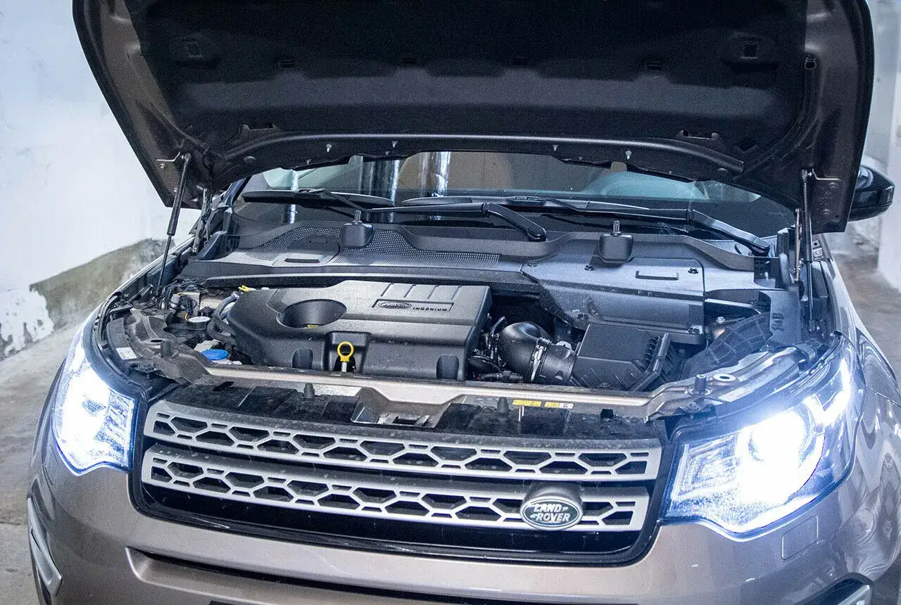 Motorraum eines Land Rover Discovery Sport 2.0 TD4. Offene Motorhaube zeigt den Motor, der auf m&ouml;gliche Probleme untersucht wird.
