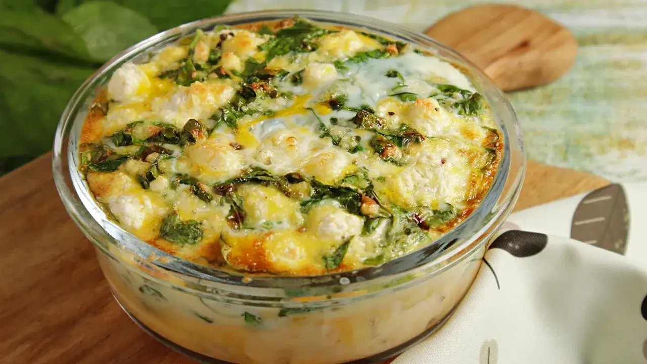 Heißer griechischer Spinat Feta Auflauf in einer Glasform, goldbraun gebacken, mit geschmolzenem Käse und frischem Spinat.