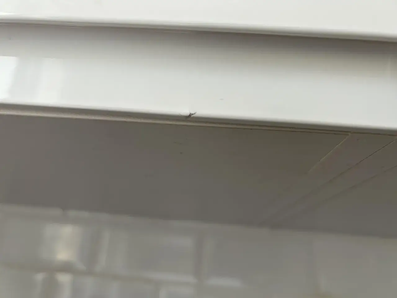 Detalle de un peque&ntilde;o rasgu&ntilde;o en un mueble lacado blanco, listo para reparar.