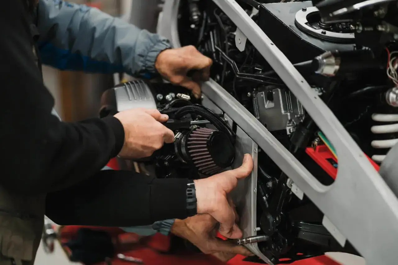Mechanicy montują nowy filtr powietrza w motocyklu. Zepsuty filtr powietrza objawy to m.in. spadek mocy.