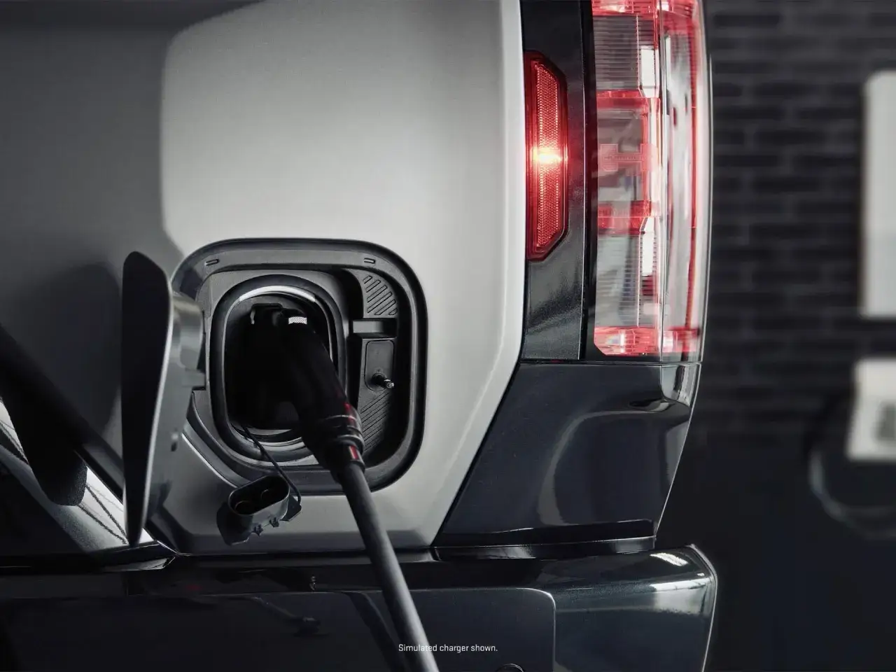 Ładowanie hummera elektrycznego. Wtyczka podłączona do portu ładowania, czerwone światło tylnej lampy sygnalizuje gotowość.