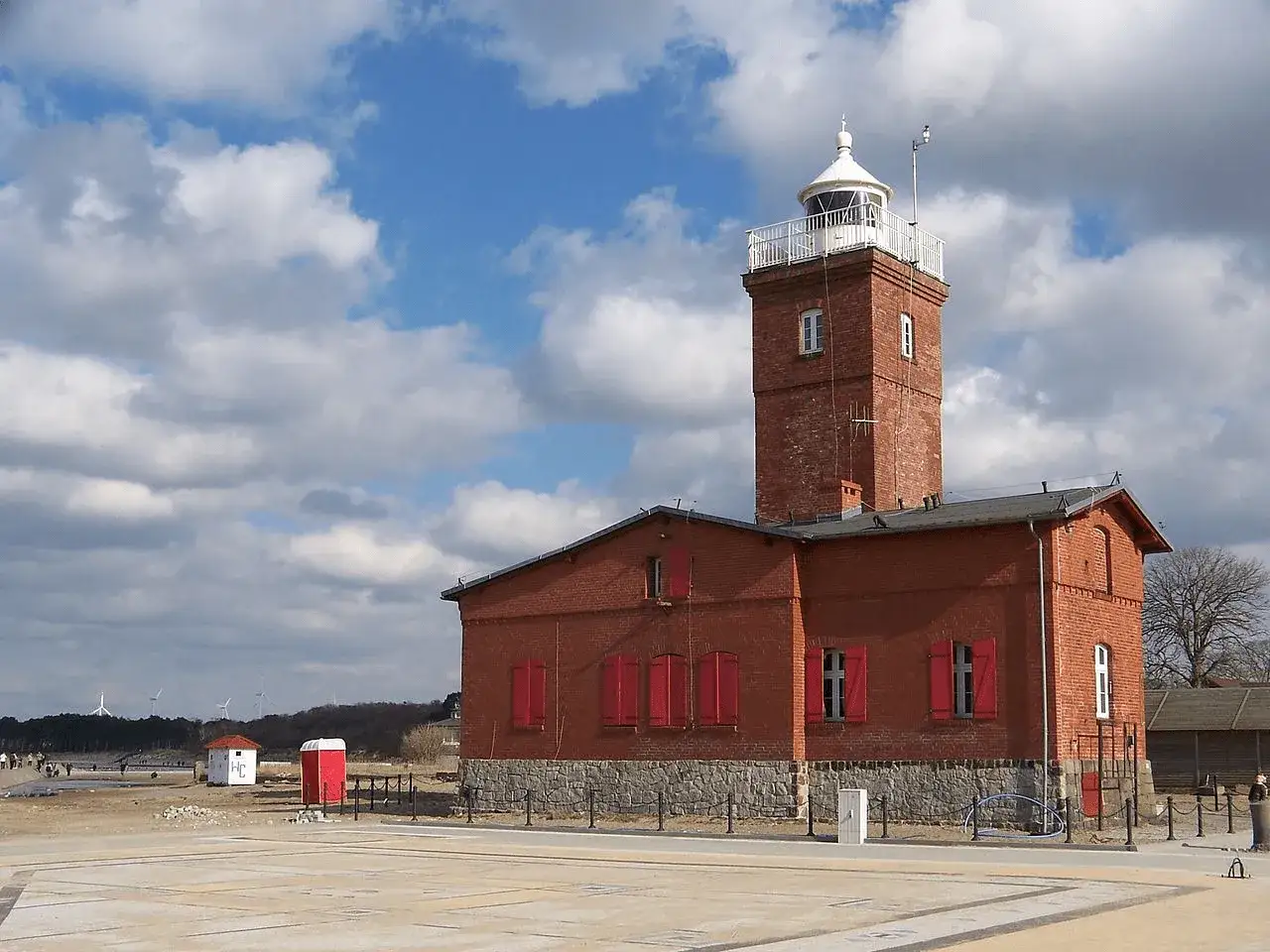 Ceglany port rybacki nad Wieprzą z charakterystyczną wieżą latarni morskiej.