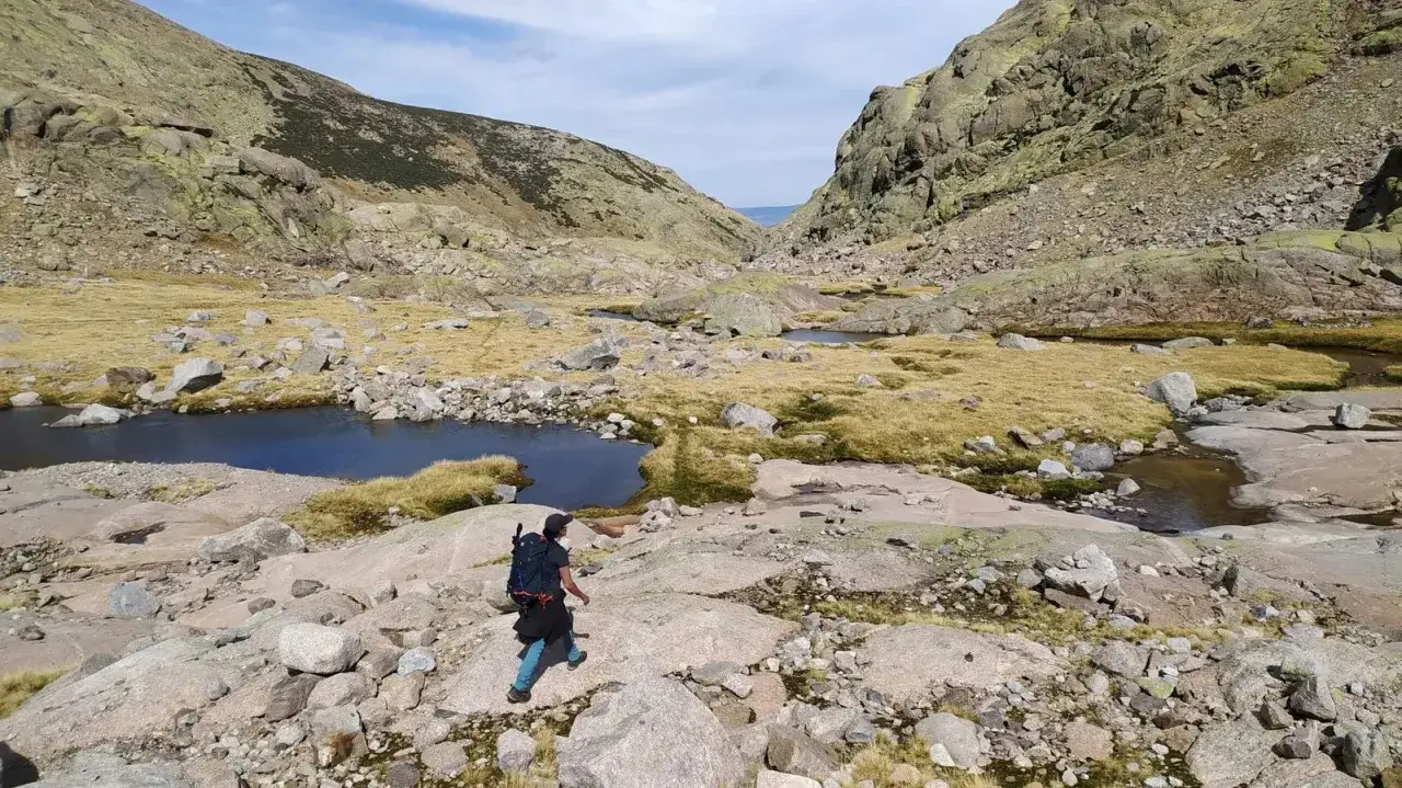 Senderista explora las impresionantes rutas de la Sierra de Gredos, rodeado de lagunas glaciares y rocas milenarias.