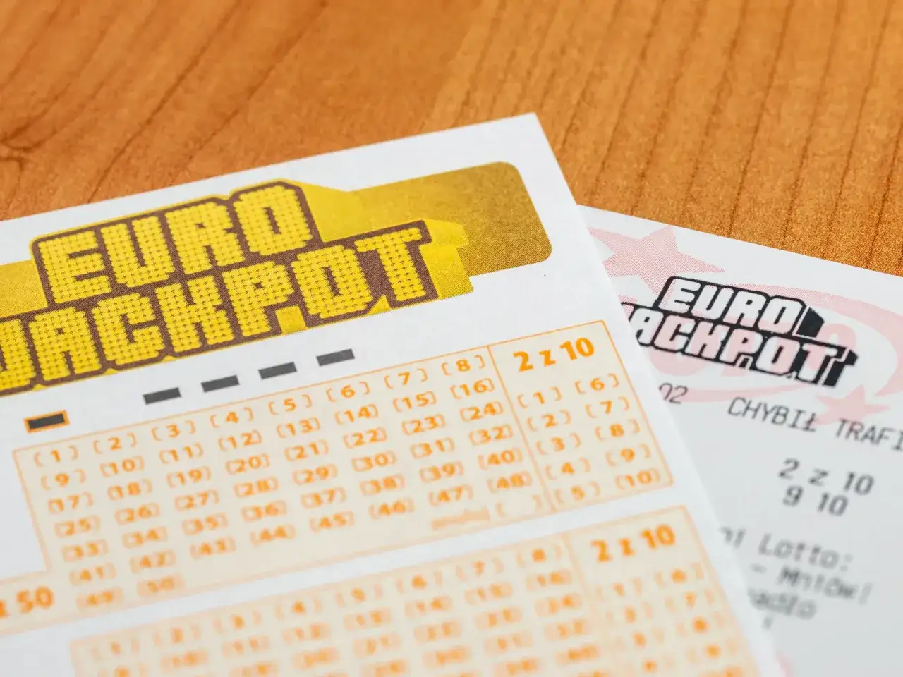 Kupony Eurojackpot leżą na drewnianym stole. Kto wie, czy właśnie te liczby przyniosą szczęście i jakie będą losowanie Eurojackpot wyniki.