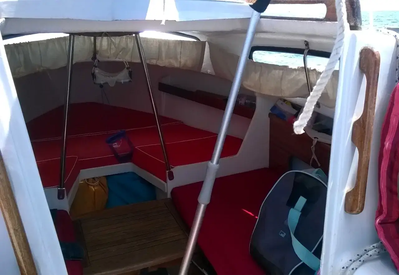 L'intérieur du voilier Edel 2 est prêt pour l'aventure, avec des coussins rouges et des sacs de rangement.