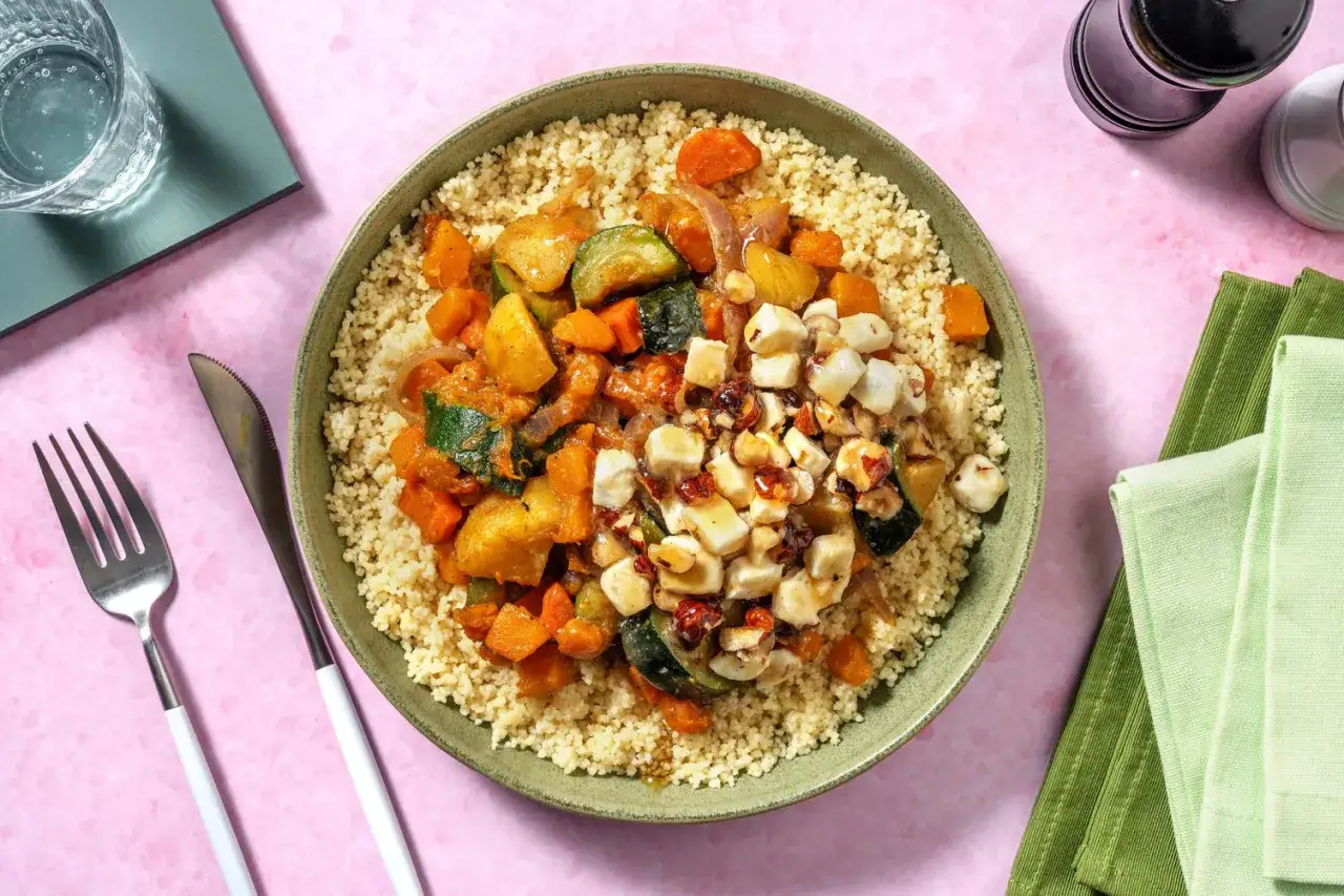 Piatto di cous cous con verdure miste, cubetti di formaggio e frutta secca, un sapore che ricorda il cous cous Marocco.