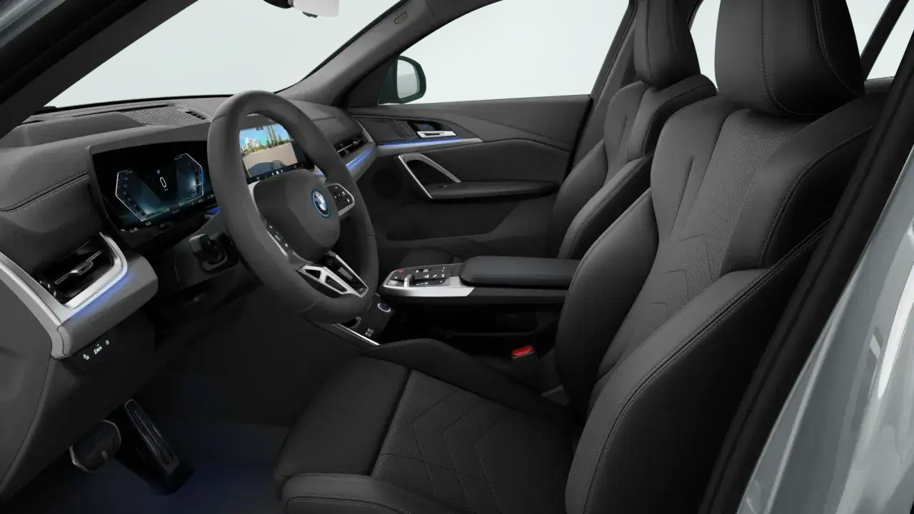 Wnętrze BMW iX2: czarne, skórzane fotele, nowoczesny kokpit z dużym ekranem i niebieskim ambientowym oświetleniem.