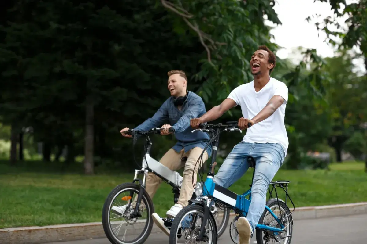 Dwóch mężczyzn śmieje się, jadąc na rowerach elektrycznych. Proste wskazówki, jak uruchomić rower elektryczny, sprawią, że jazda będzie przyjemnością.