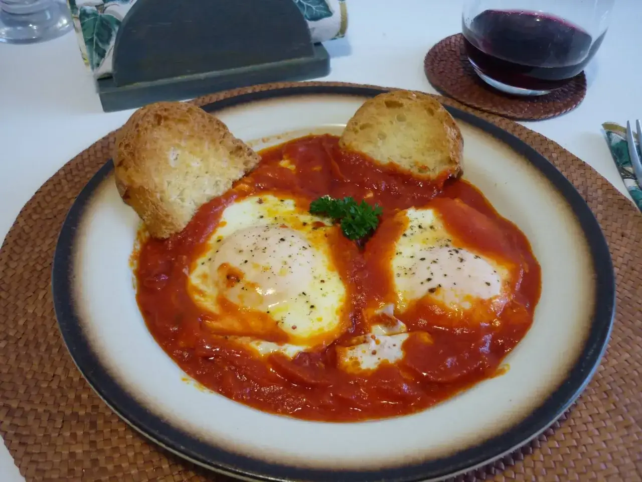 Uova in trippa marchigiana servite con pane tostato e un bicchiere di vino rosso.