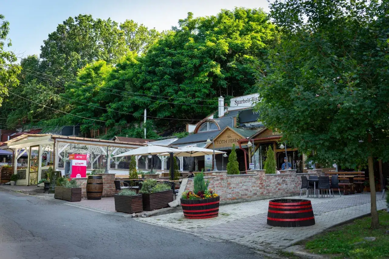 Urokliwe **Eger i okolice atrakcje** zachęcają do odpoczynku. Widać tu restauracje z ogródkami, zielone drzewa i kamienne detale.