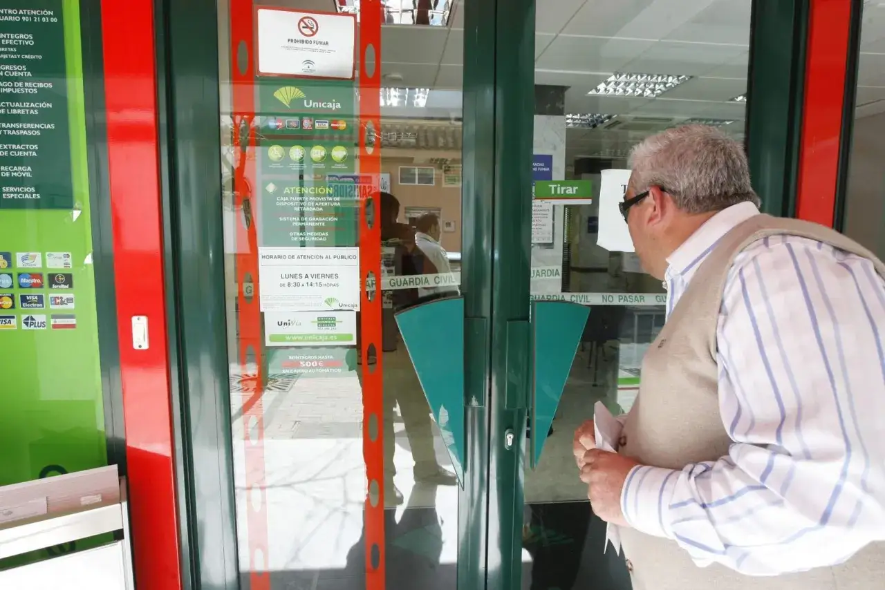 Un hombre mira la entrada de una sucursal de Unicaja, pregunt&aacute;ndose qu&eacute; bancos adelantan las pensiones este mes.