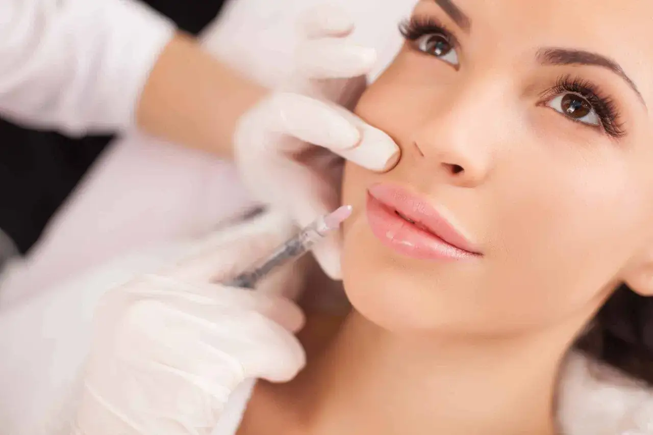 Primo piano di una donna che riceve un filler labbra. Informarsi sulle controindicazioni prima del trattamento.