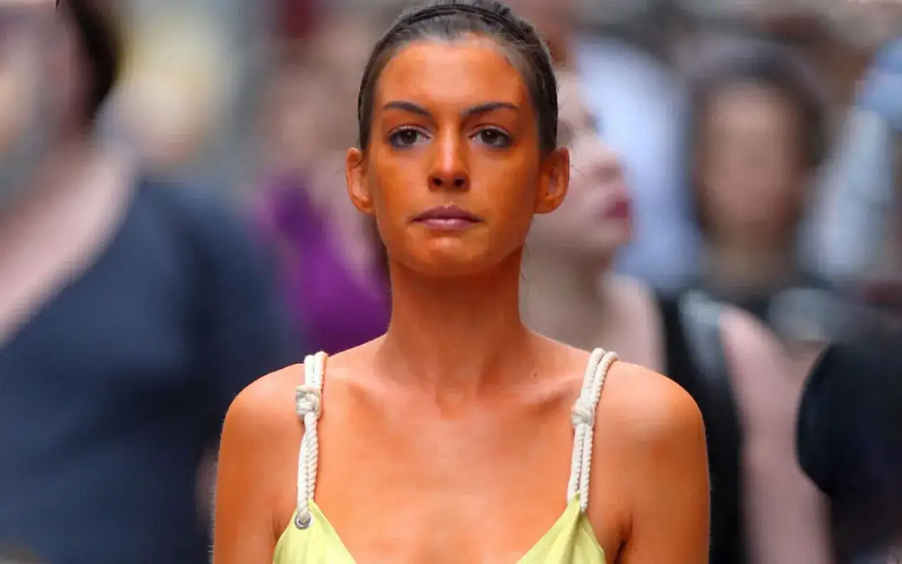 Donna con un'abbronzatura arancione intensa, quasi artificiale, cammina tra la folla sfocata.
