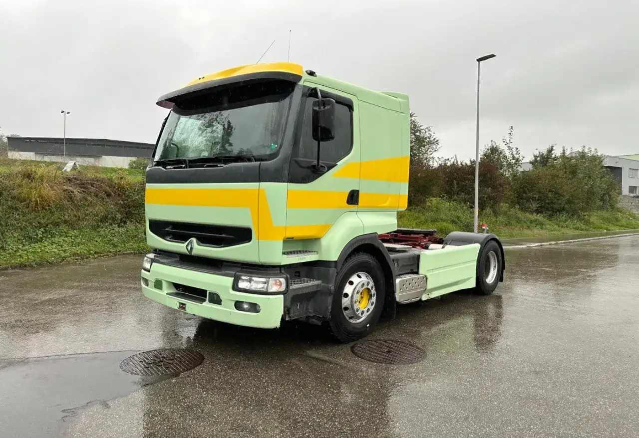 Ciężarówka Renault Premium w pastelowej zieleni z żółtymi pasami, gotowa do drogi po deszczu.