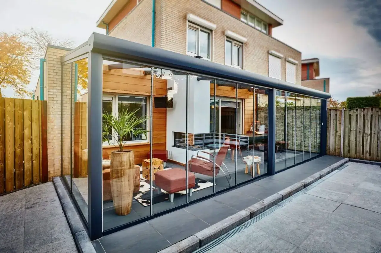 Modern glass enclosure seamlessly unir terraza y salon, creating a bright, inviting space with fireplace and comfortable seating.