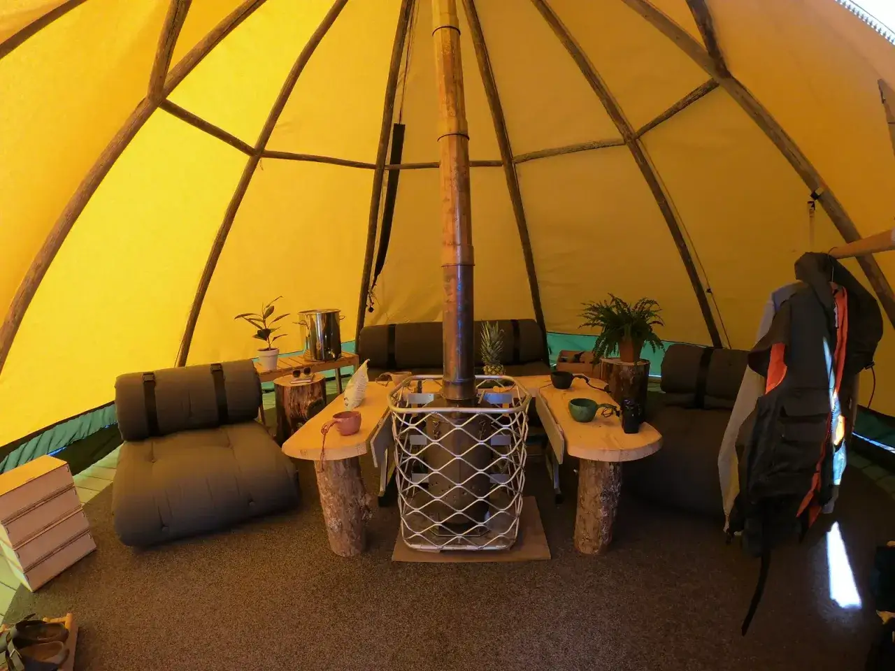 Mysig interi&ouml;r i ett t&auml;lt p&aring; Sorsele camping med vedkamin, sittplatser och tr&auml;bord.