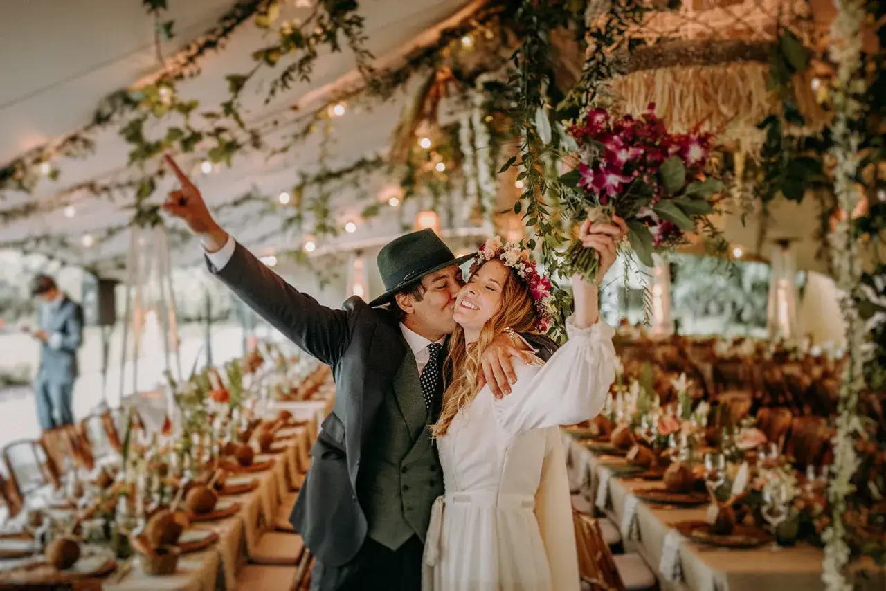 Novios celebran su unión bajo un toldo decorado. El hombre besa a la mujer, quien sostiene un ramo. El significado de 22 años de casados se refleja en su alegría.