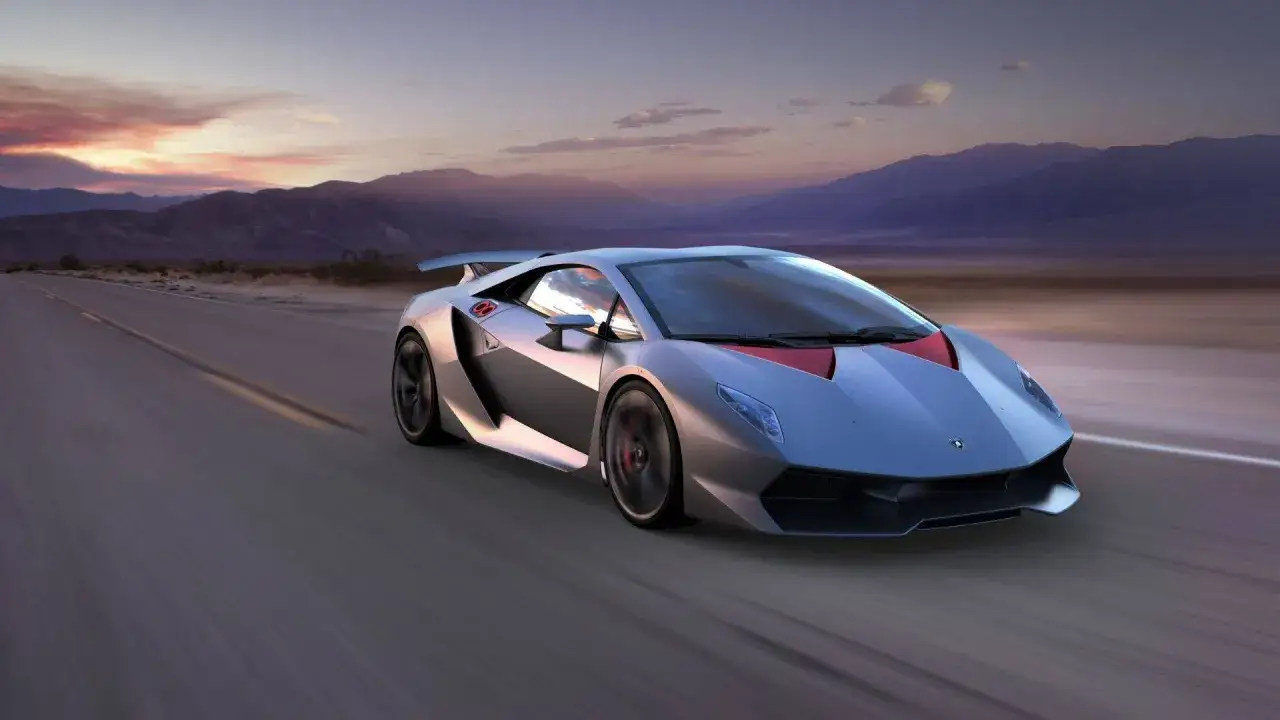 Srebrny Lamborghini Sesto Elemento pędzi pustynną drogą o zachodzie słońca.