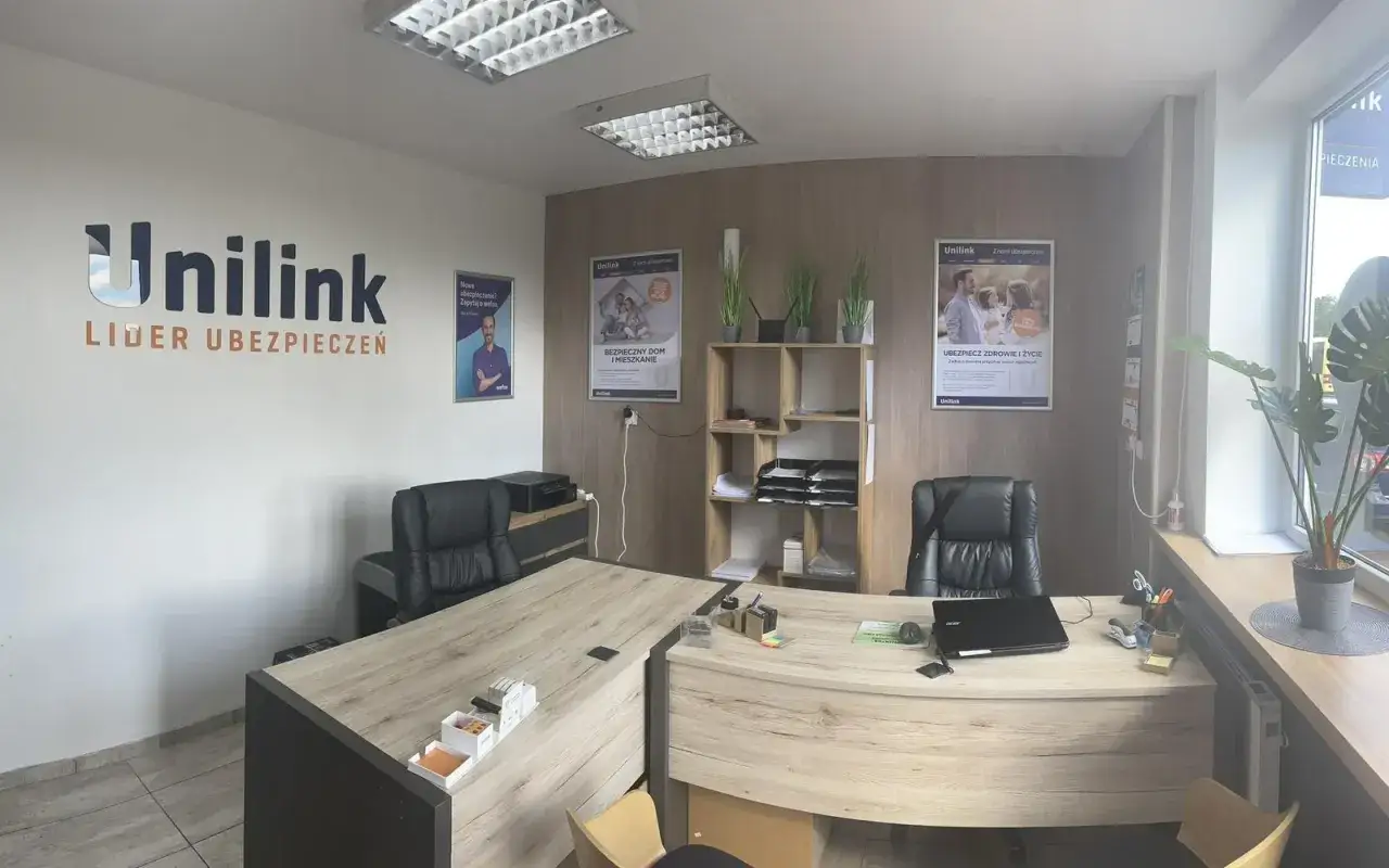 Biuro firmy Unilink z logo, plakatami ubezpieczeniowymi i meblami biurowymi.