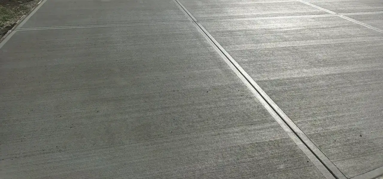Szary beton szczotkowany z wyraźnymi liniami podziału, tworzący gładką, antypoślizgową powierzchnię.