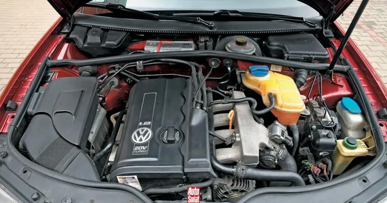 Silnik 1.8t Volkswagena z widocznym logo i oznaczeniem 20V TURBO. Widać elementy układu chłodzenia i akumulator.